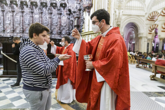 sacerdote joven dando la comunion